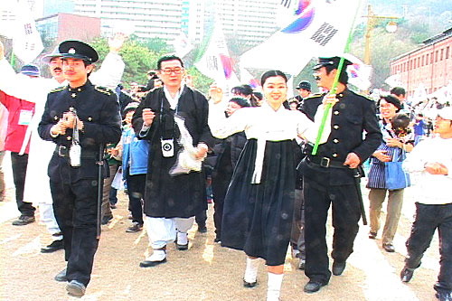 치마저고리를 입고 선봉에 서서 만세를 외치는 유관순 열사옆에 일본 순사가 따라가고 있다. 